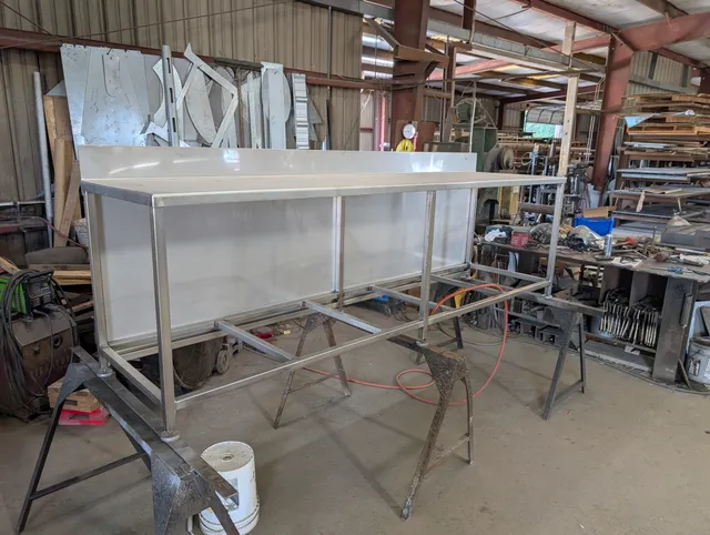 Stainless steel work counter with white surface being fabricated in the shop